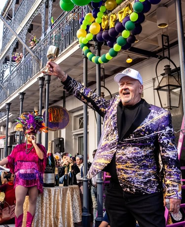 Person standing in front of the hotel in a colorful suit.