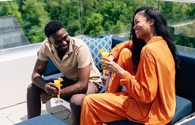 Two guests enjoying drinks together on an outdoor terrace.